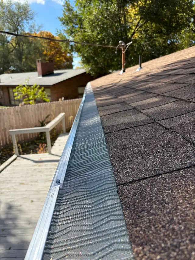 Close-up of gutter guard mesh fitted over a K-style gutter on a shingle roof