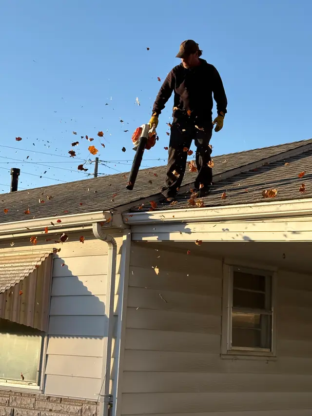 Technician on a roof clearing a gutter run